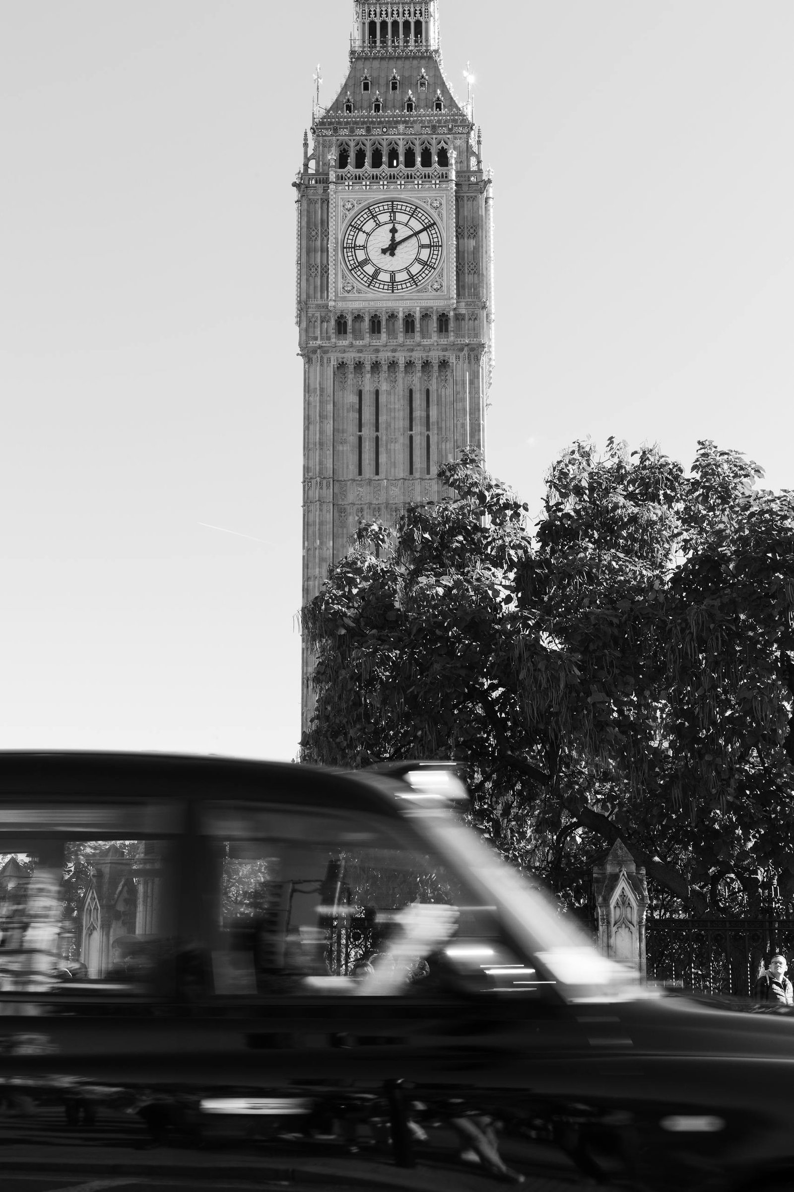 Dramatic black and white photo of Elizabeth Tower with a blurred black cab passing by in London.