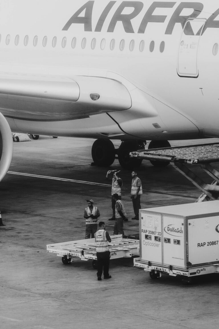 Ground crew loading cargo onto an airplane at the airport, black and white scene.