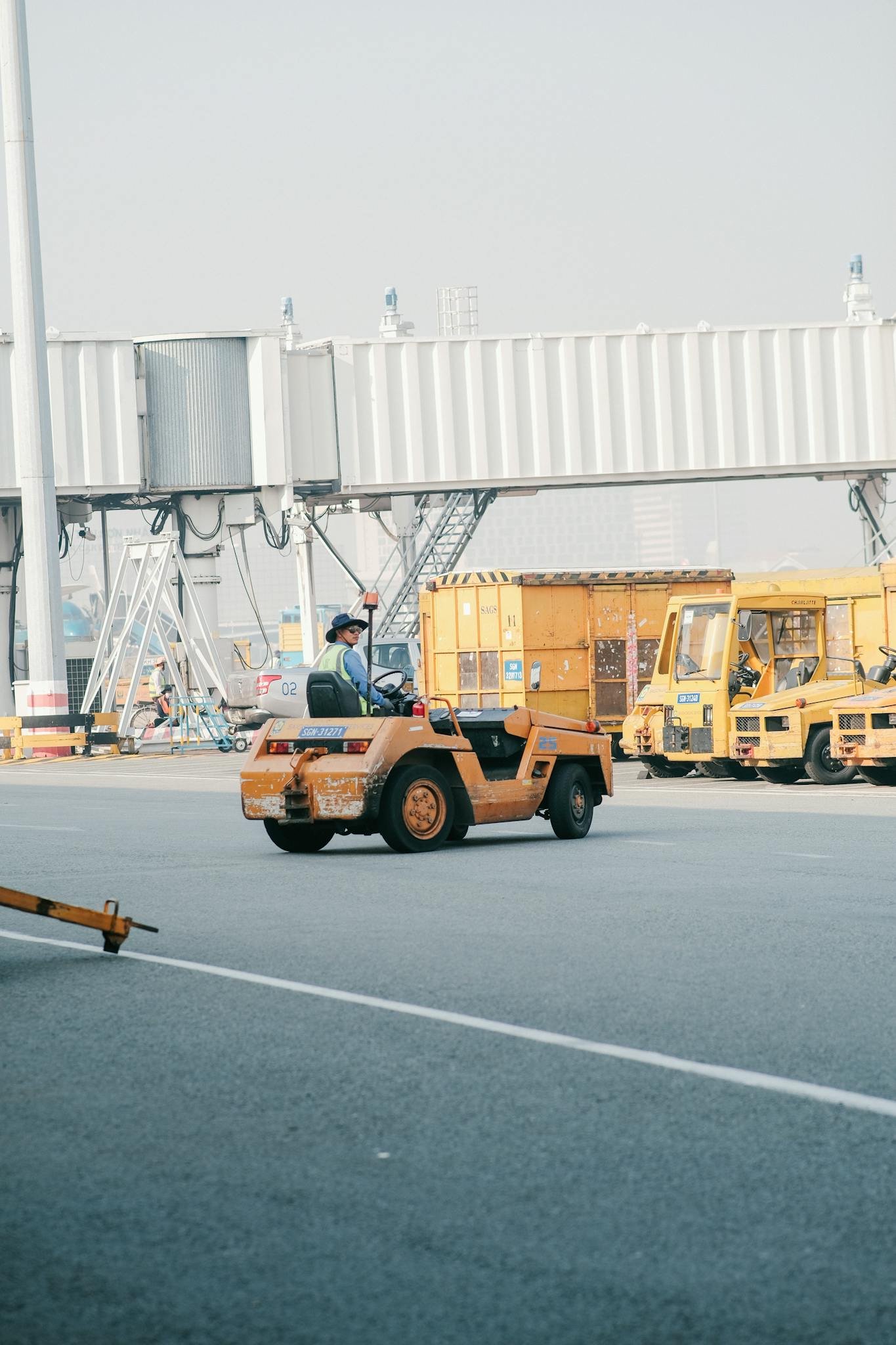 Ground crew operating vehicles on an airport tarmac, showcasing busy airport logistics.