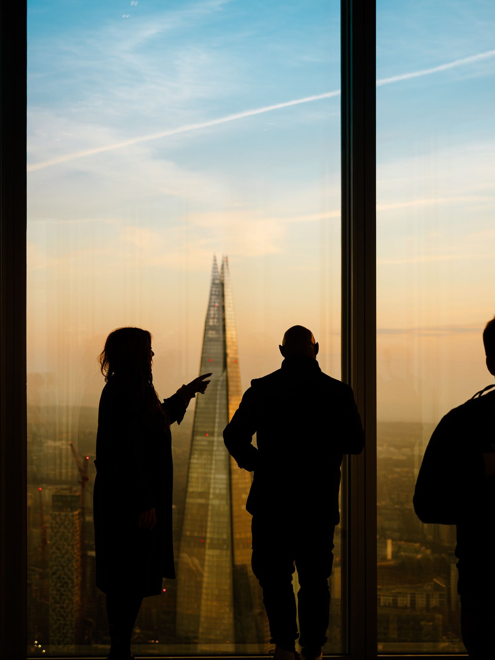Silhouettes of people viewing The Shard from inside, with a picturesque sunset in the background.